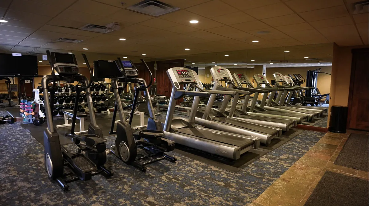 A bright, modern fitness center featuring elliptical machines, treadmills, and a rack of dumbbells. The space is well-lit, motivating, and designed for both individual and group workouts, inviting residents to exercise and socialize.